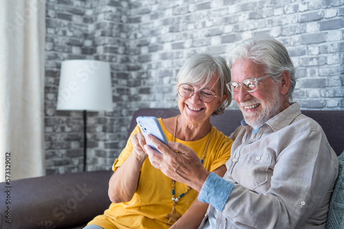 Elderly grandfather and grandmother spend time having fun using smartphone apps, middle-aged wife enjoy online entertainments, taking selfie with old husband, older generation and modern tech concept.