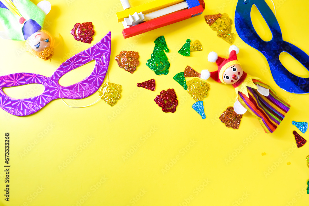 Obraz premium Carnival party background with carnival mask and clown hat. Birthday celebration concept. Top view with copy space carnival, party and Purim celebration concept (jewish carnival holiday) over yellow 