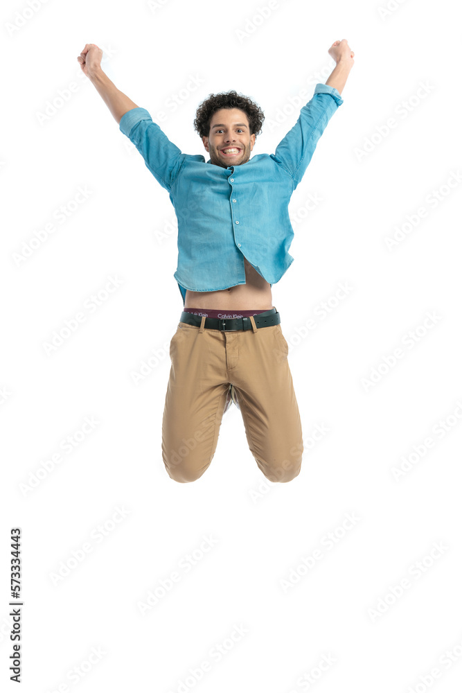 dynamic casual man holding arms above head and jumping in the air