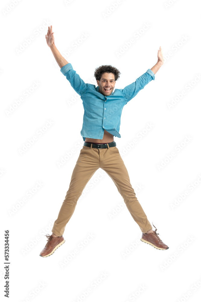 attractive enthusiastic man jumping in the air and holding arms above head