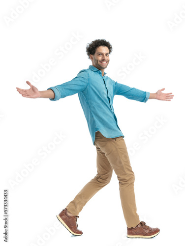 happy arab man in denim shirt opening arms, smiling and walking