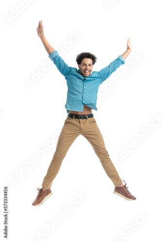 attractive enthusiastic man jumping in the air and holding arms above head