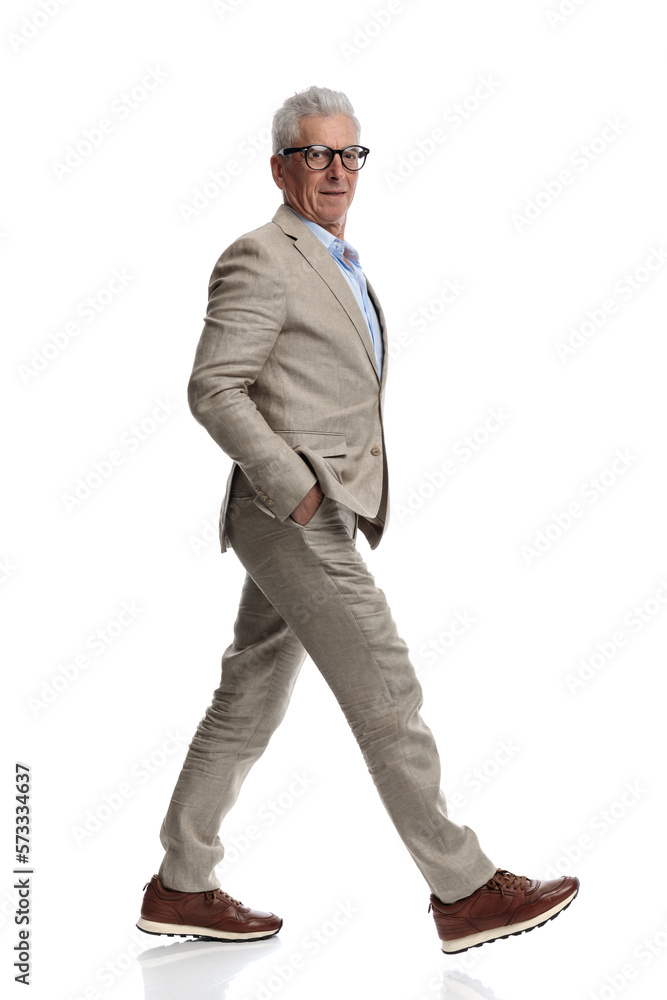 elegant man in suit with glasses walking with hands in pockets elegant man in suit with glasses walking with hands in pockets