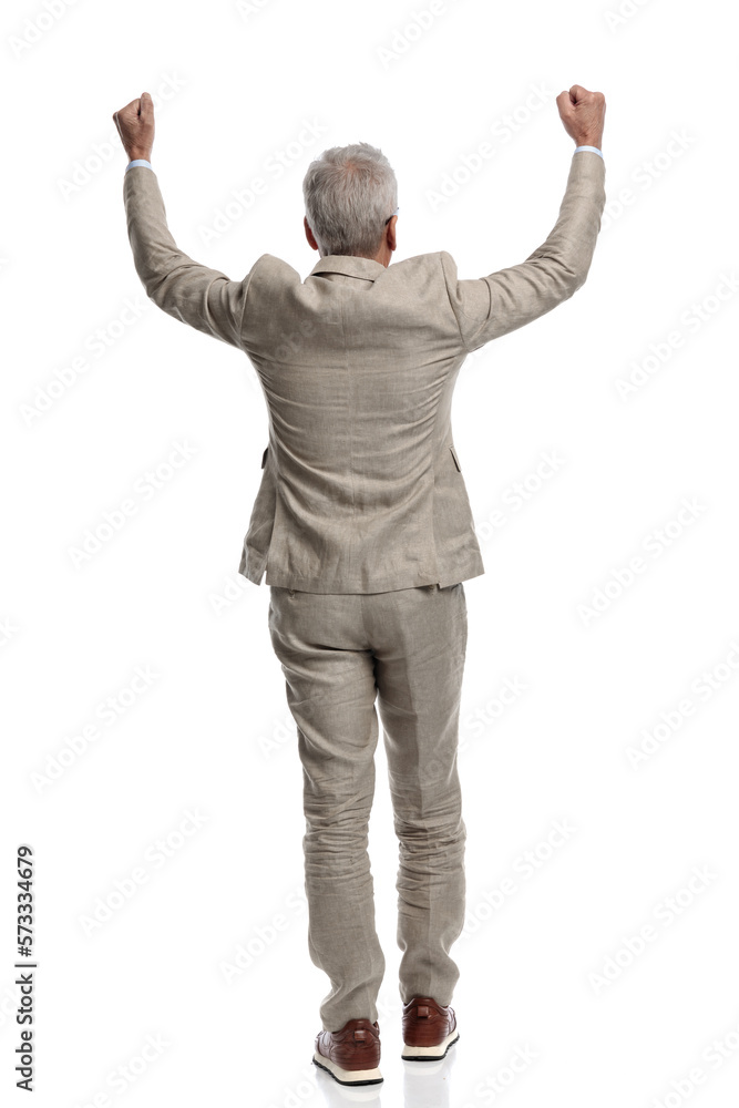 back view of old man in his 60s holding arms above head and cheering back view of old man in his 60s holding arms above head and cheering