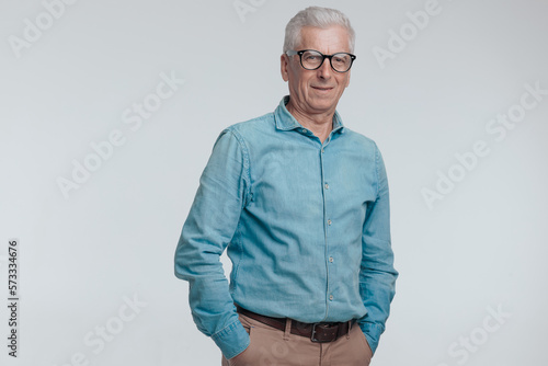 Fotografie portrait of casual man in his 60s holding hands in pockets and smiling