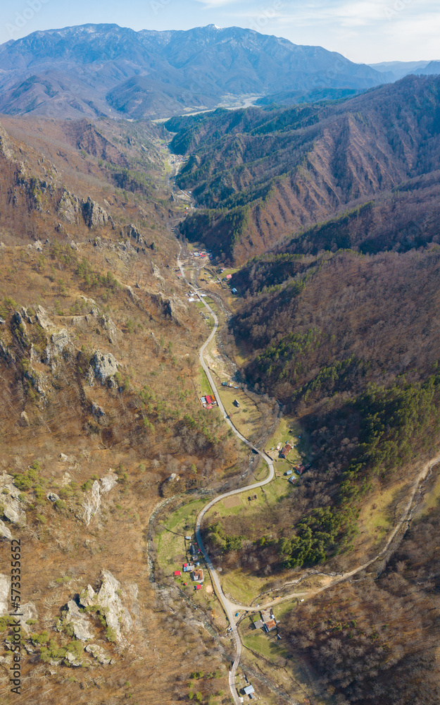 Aerial vertical drone view above Calinesti valley in springtime. The small settlement is surrounded by beech forests and eroded cliffs pointing out of the trees. Rural Romania. Carpathia. Aerial vertical drone view above Calinesti valley in springtime. The small settlement is surrounded by beech forests and eroded cliffs pointing out of the trees. Rural Romania. Carpathia.