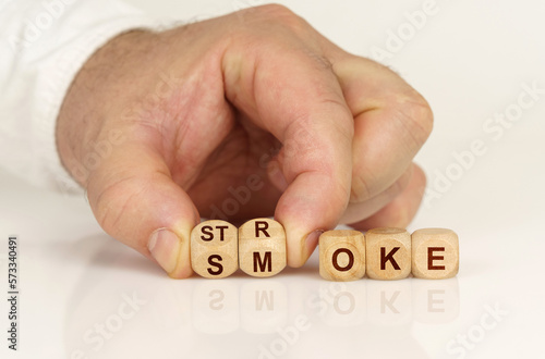 On the reflective surface in the hands of a man are cubes with the inscription - STROKE SMOKE