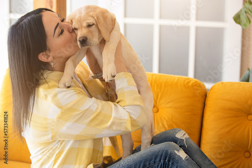 Labrador puppy with young woman in home interior