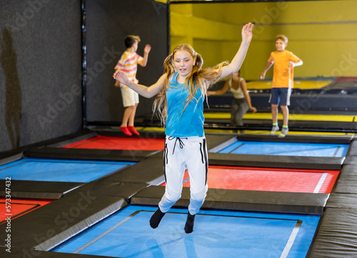 Happy cute little girl jumping on a trampoline indoors