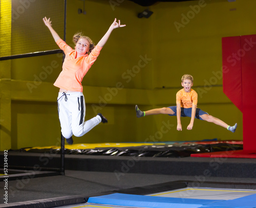 Smiling carefree teenage girl having fun during free-jumping session in indoor trampoline arena..