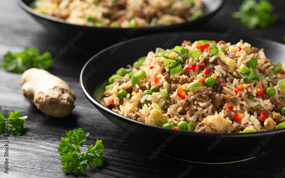 Asian Beef Fried Rice with eggs and vegetables in black bowl Asian Beef Fried Rice with eggs and vegetables in black bowl