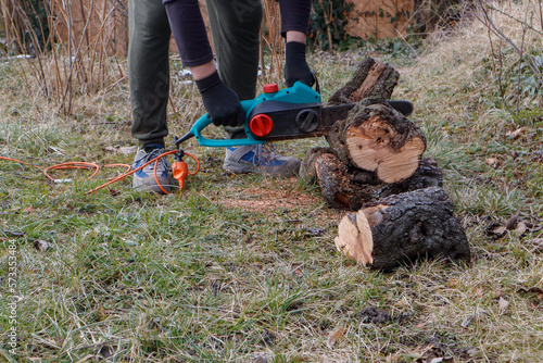 A man works by cutting a sick tree in the garden with a chainsaw