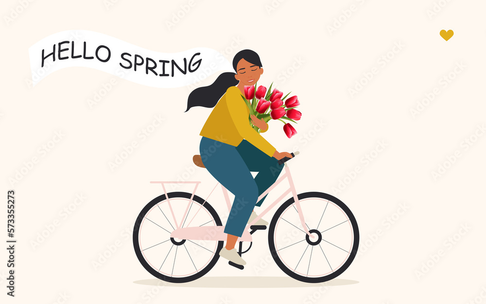 A happy girl with a bouquet of tulips in her hand rides a bicycle and rejoices at the beginning of spring. Pretty cyclist enjoying warm weather, doing physical and mental health. 