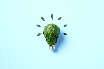 Light bulb with green leaves on blue background. Sustainable energy, Save the Planet, Earth hour concept.