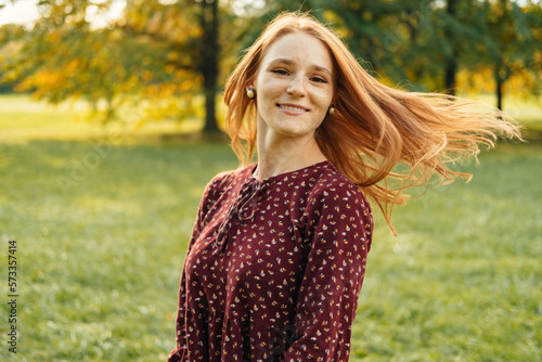 Fotografi Dynamic portrait of a red head cheerful woman turning her head to the camera outdoors