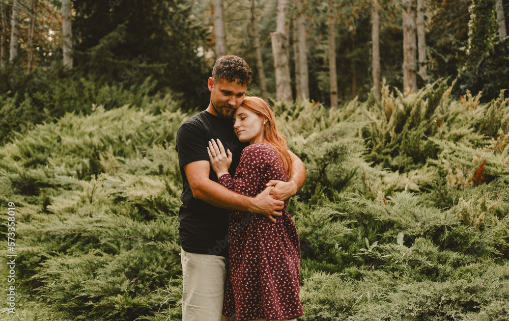 Cute young embracing couple enjoys each others presence in a green park outdoors. Cute young embracing couple enjoys each others presence in a green park outdoors.