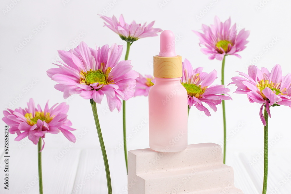 Cosmetic bottle on wooden table with pink daisy flowers Cosmetic bottle on wooden table with pink daisy flowers