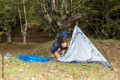 Wallpaper Mural Young woman with outdoor gear setting up his tent in a clearing after a day of hiking in the woods Torontodigital.ca