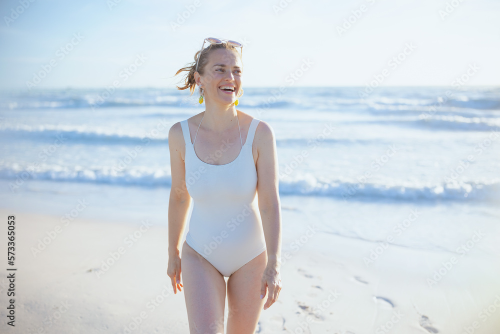 smiling stylish female in white swimsuit at beach relaxing smiling stylish female in white swimsuit at beach relaxing