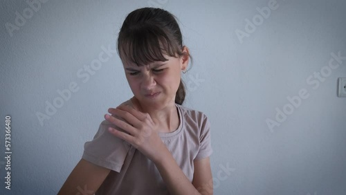 Teen stress because of painfull shoulder. A young frustrated teen feel the pain in her shoulder after trauma in the flat.