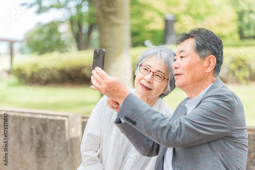 屋外でスマホを使って写真や動画を撮る高齢者夫婦

