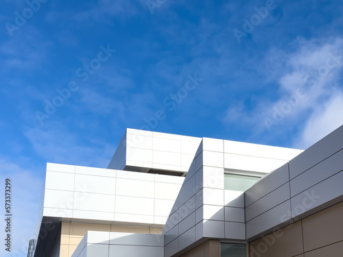 The exterior wall of a grey contemporary commercial style building with aluminum metal composite panels and glass windows. The futuristic building has engineered diagonal cladding steel frame panels.