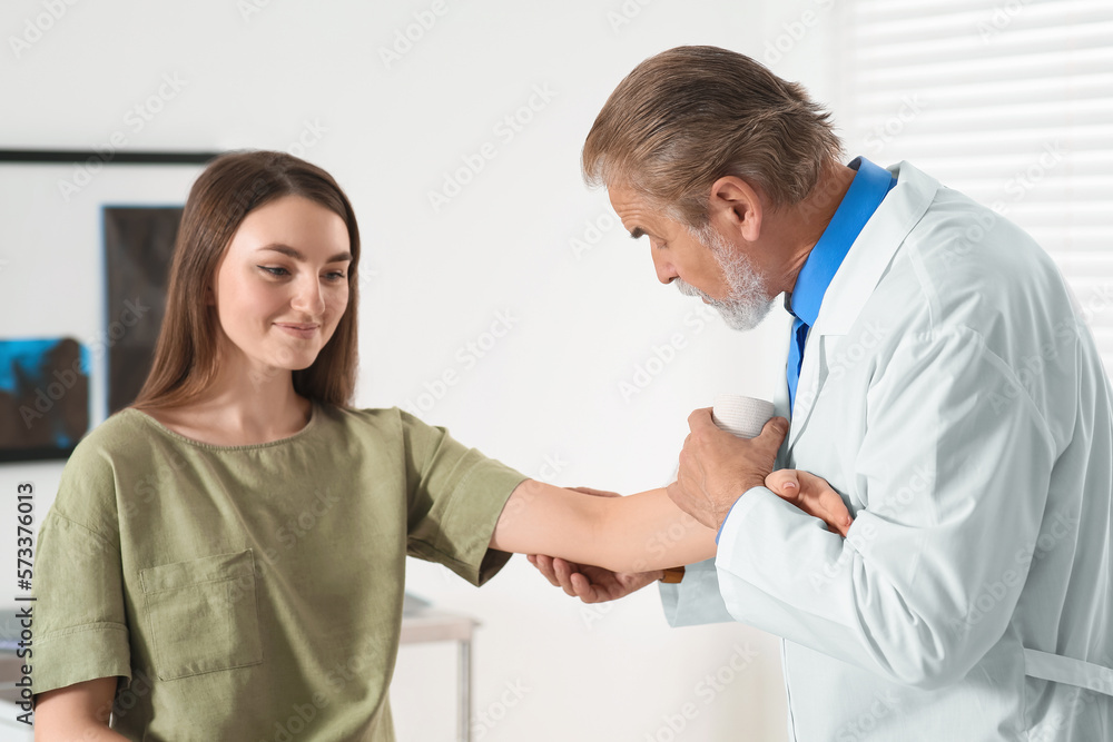 Orthopedist examining patient with injured arm in clinic Orthopedist examining patient with injured arm in clinic