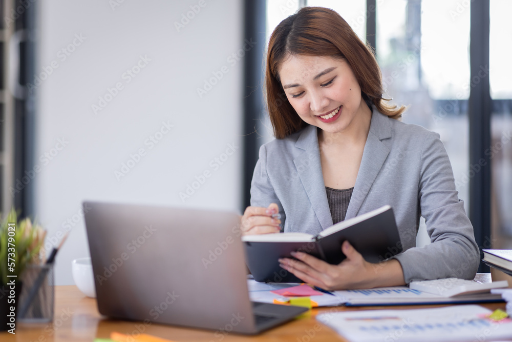 Young asian business woman manager accounting analyst checking bills, analyzing sales statistics management, taxes financial data documents or marketing report papers working in office using laptop. Young asian business woman manager accounting analyst checking bills, analyzing sales statistics management, taxes financial data documents or marketing report papers working in office using laptop.