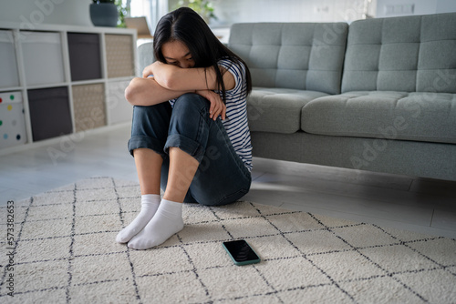 Εκτύπωση καμβά Upset unhappy sad asian woman sitting near smartphone on floor at home