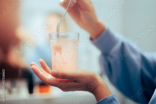 Woman Mixing Powder Medicine in a Glass of Water. Person preparing a soluble drink with a nutritional supplement 
 photo