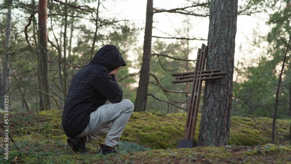 Man kneeling and crying in front of a wooden cross. Grief and loss Man kneeling and crying in front of a wooden cross. Grief and loss