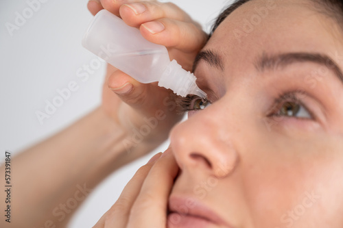 Caucasian woman dripping moisturizing drops into her eyes. 