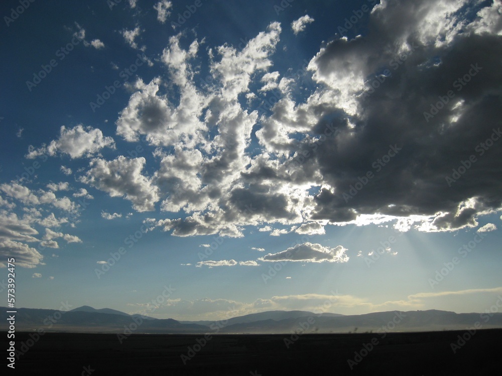 Dark Clouds Covering Sunny Sky with Mountains in Distance Dark Clouds Covering Sunny Sky with Mountains in Distance