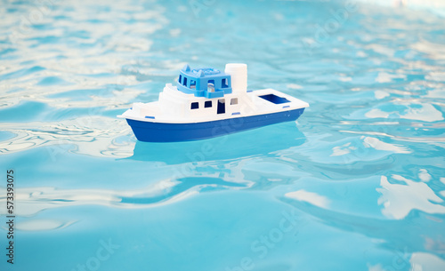 Toy ship, boat in swimming pool blue water. Concept of kid games, leisure time in summer vacations, travel, tourism, cruise concept. Copy space.