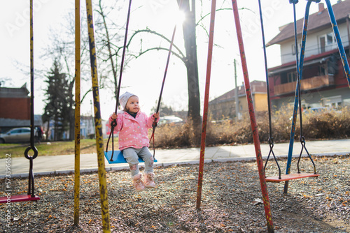 A one young baby girl is swinging on swing in the park during the day