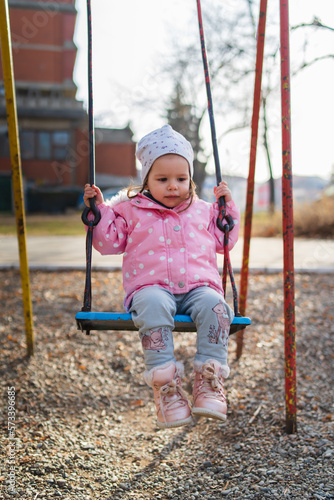 A one young baby girl is swinging on swing in the park during the day