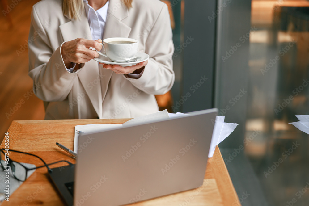 Close up of businesswoman having coffee break time during working day in cafe