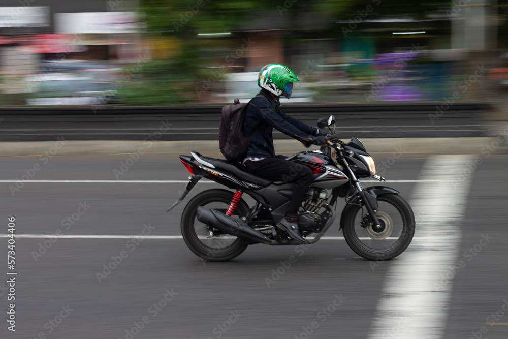 Photo of a young man riding a sports motorbike, taken with the blur technique