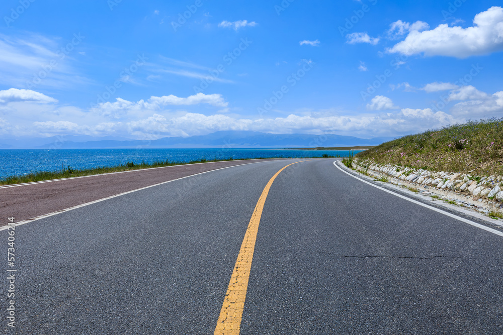 Naklejka premium Asphalt road and lake with sky clouds natural scenery in Xinjiang, China.