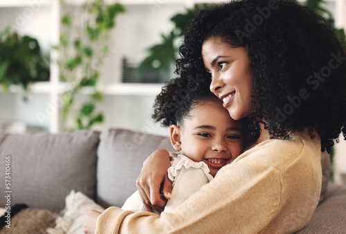 Hug, love and black family by girl and mother on a sofa, happy and relax in their home together. Mom, daughter and embrace on a couch, cheerful and content while sharing a sweet moment of bonding