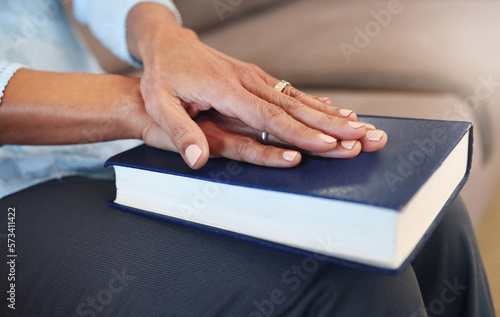 Bible, prayer and hands of old woman in living room for religion, book and Christian faith. Spiritual, God and worship with senior lady praying with holy text at home for wellness, believe and goal © Allistair F/peopleimages.com