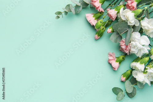 A bouquet of white and pink carnations with eucalyptus branches on a soft green background.