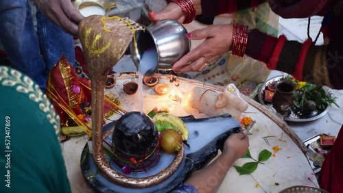 Hand of a devotee Offering water milk to Shivling or Lord Shiva on the occasion of Maha Shivratri Festival celebration in India photo