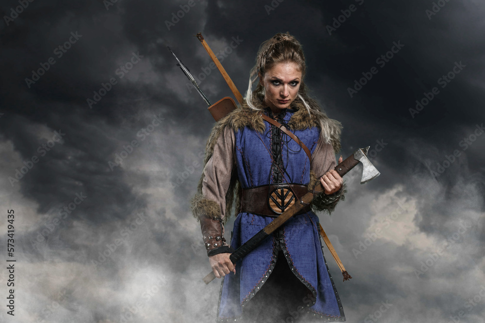 Beautiful female viking woman warrior in battle with ax and bow with arrows. Amazon fantasy blonde