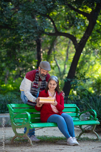 Indian man giving surprise gift to woman at park.