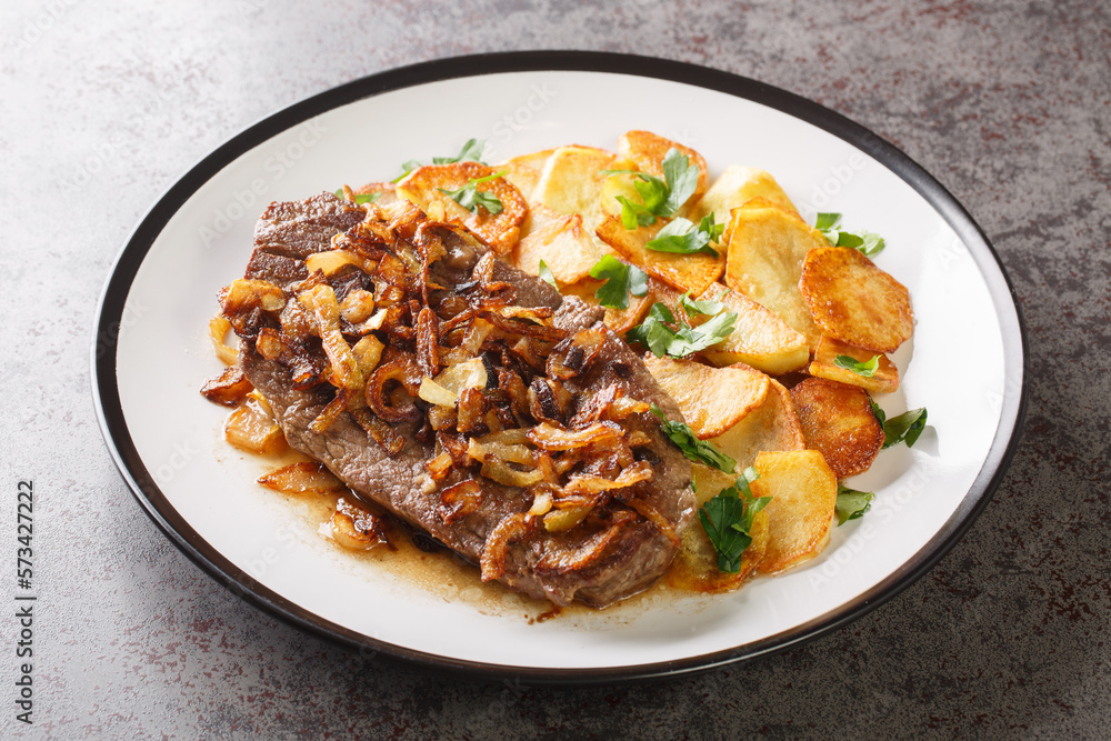 Original and Authentic German Zwiebelrostbraten with onion gravy and fried potatoes Bratkartoffeln closeup on the plate on the table. Horizontal Original and Authentic German Zwiebelrostbraten with onion gravy and fried potatoes Bratkartoffeln closeup on the plate on the table. Horizontal