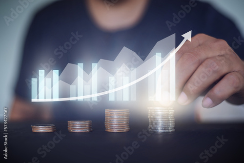 Man stacking  a coin with growing graph, money saving and  investment concept. photo