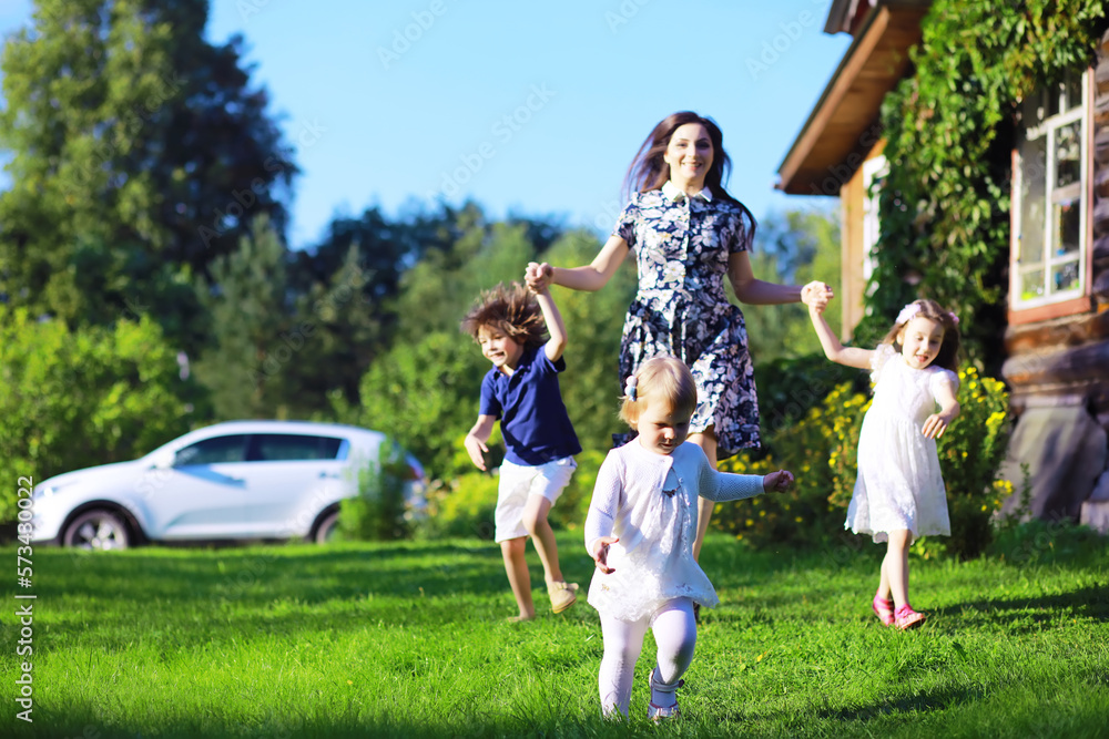 Obraz premium Young large family on a summer morning walk. Beautiful mother with children is playing in the park.