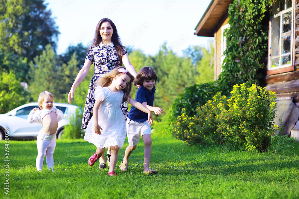 Young large family on a summer morning walk. Beautiful mother with children is playing in the park. Young large family on a summer morning walk. Beautiful mother with children is playing in the park.