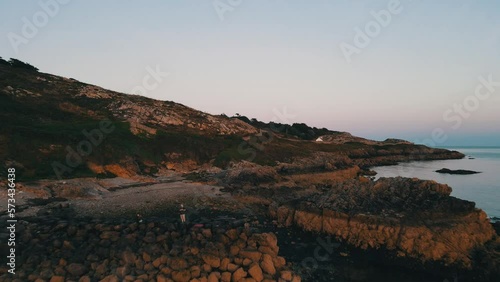 Stunning aerial footage captures Standup paddleboarding at sunset in Howth Co. Dublin surrounded by cliffs, sun kissed rolling waves and calm skies all at golden hour. photo